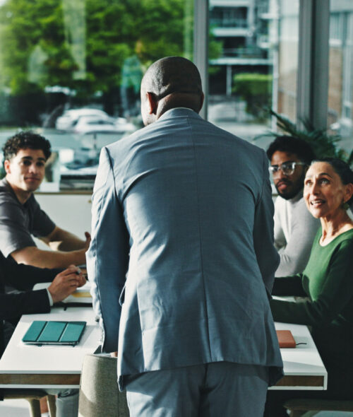 Man, presentation and group at office meeting, discussion and review with attention at finance company. Person, speaker and back with team, feedback and planning for strategy at investment agency