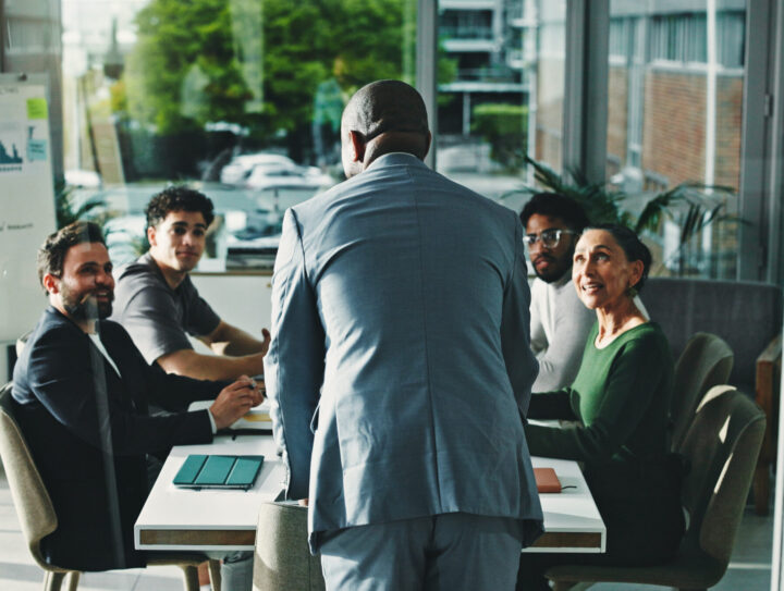 Man, presentation and group at office meeting, discussion and review with attention at finance company. Person, speaker and back with team, feedback and planning for strategy at investment agency